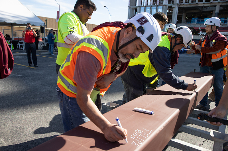 Construction team workers signing the final beam.