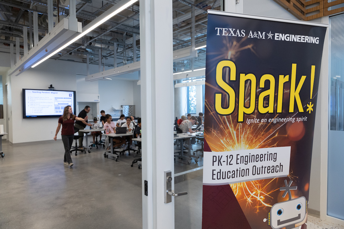 A Texas A&M Engineering "Spark!" banner marks a PK-12 engineering education outreach event in a modern classroom with students and educators engaged in learning activities.